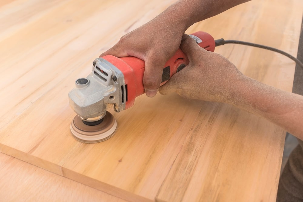 Using an angle grinder to level the surface of a sheet of plywood