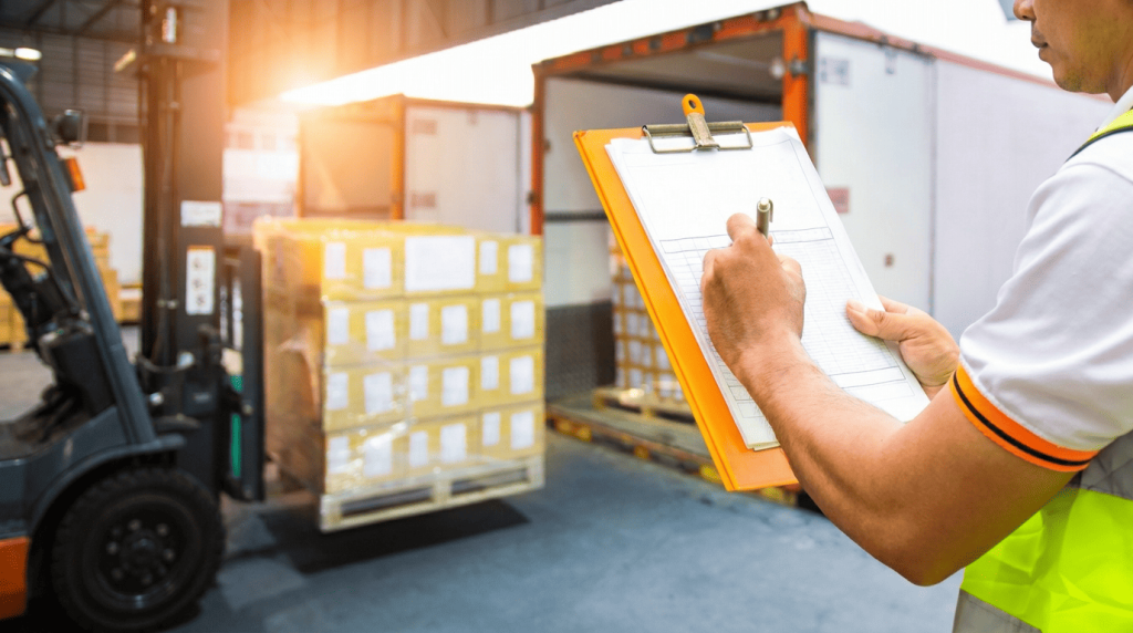 Warehouse worker in a safety vest writing on a clipboard