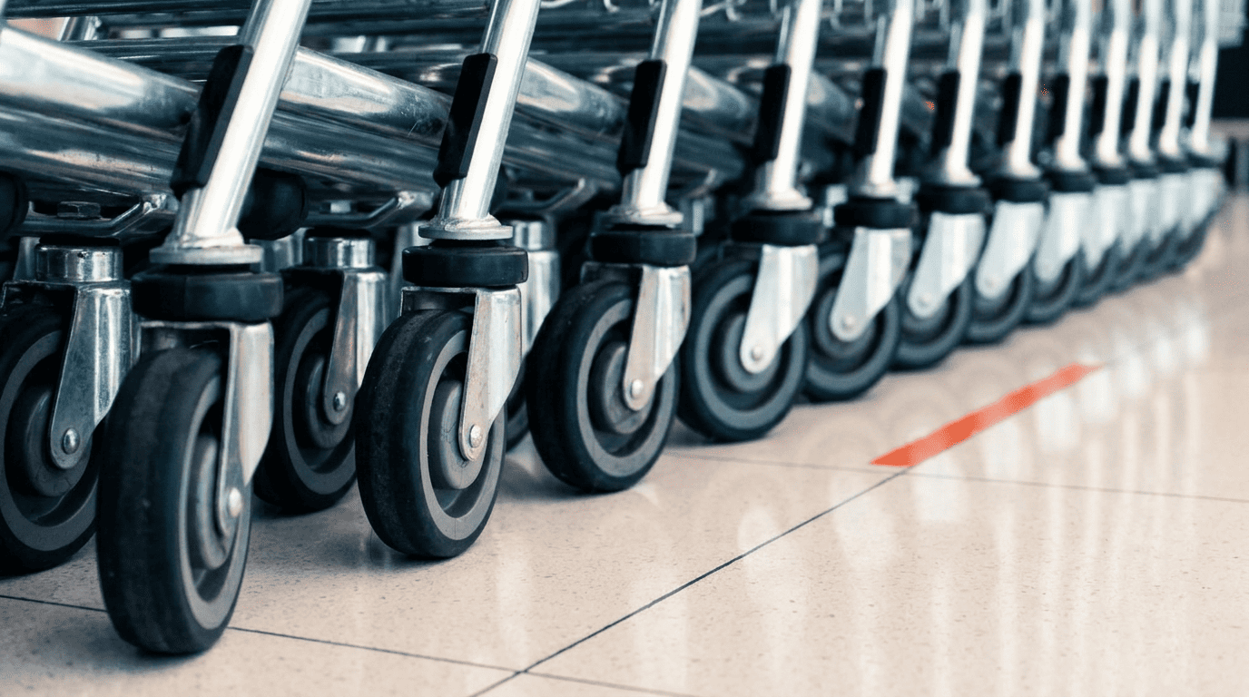 Close-up of a row of shopping caster wheels on a tiled floor