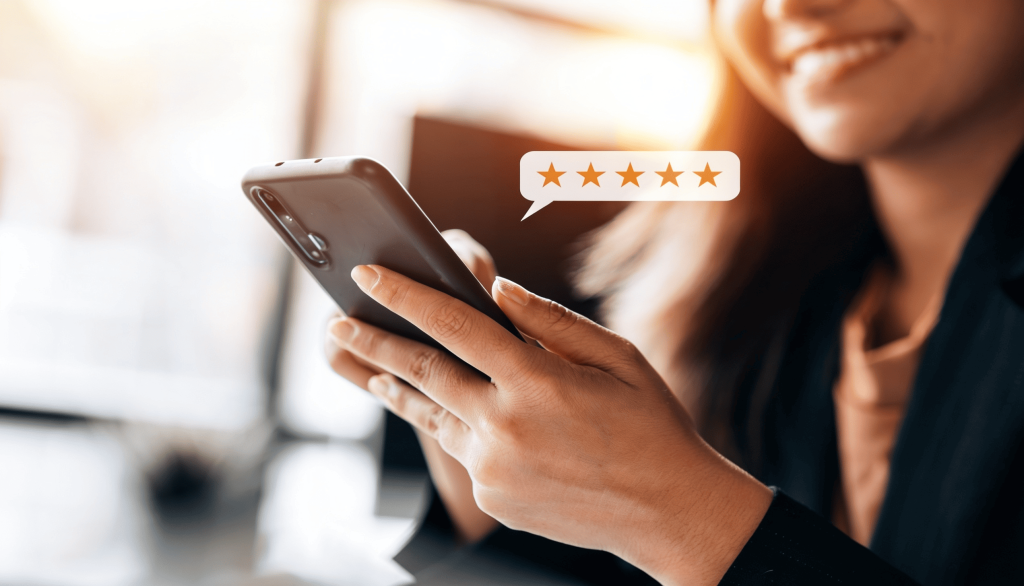 A smiling woman holding a smartphone displaying a five-star customer review notification in a speech bubble