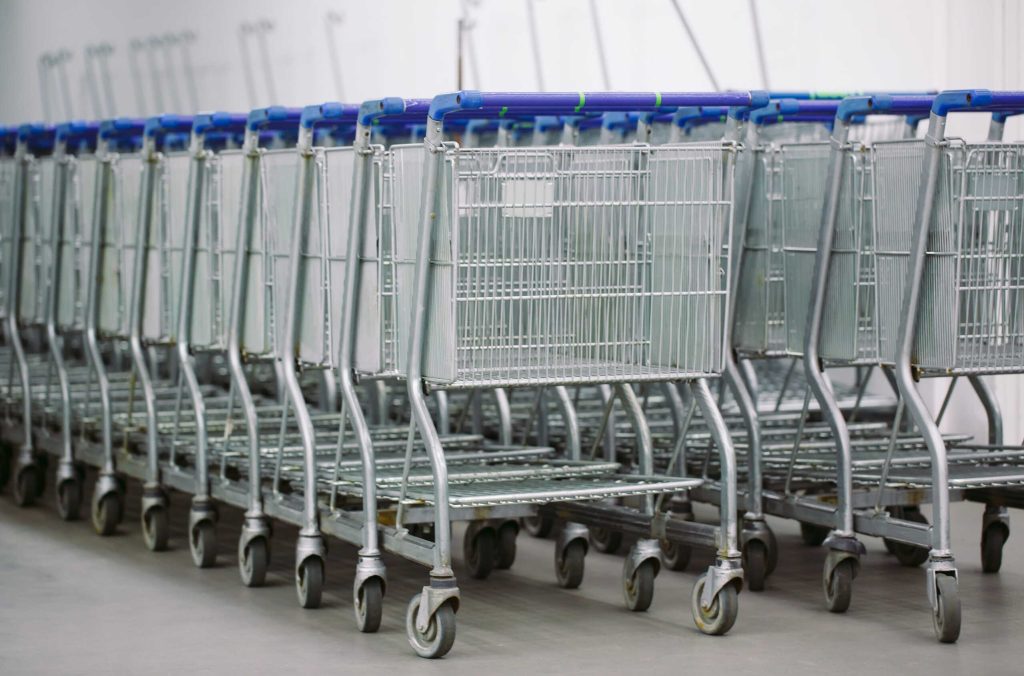 Long row of metal shopping carts and transport trolleys neatly nested together on a polished concrete floor